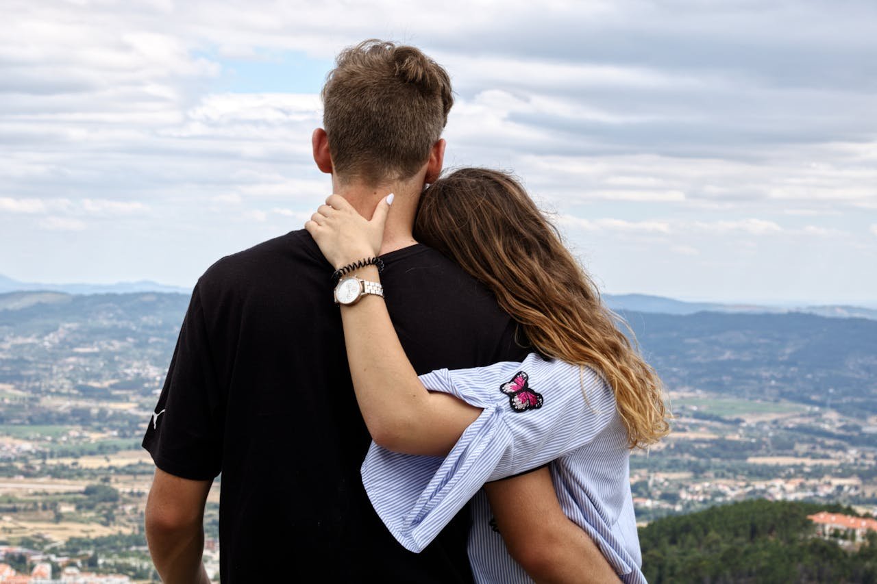 A couple embraces while enjoying a scenic view from a hillside. Perfect for travel and romance themes.