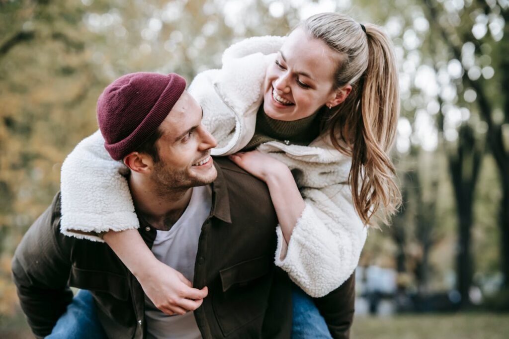 Cheerful couple embracing and enjoying time together on blurred background of trees in park